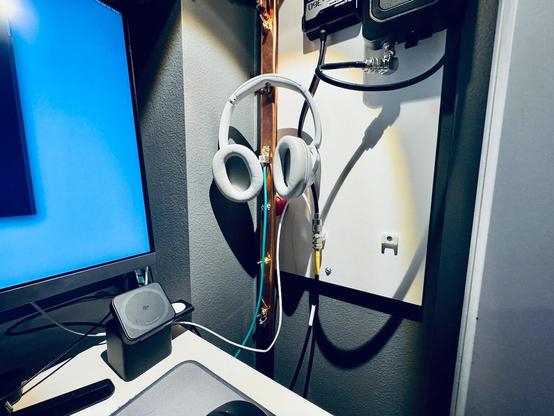 Headphones hanging off the thumbscrew of a long vertically mounted copper bar with various wires attached to it.
