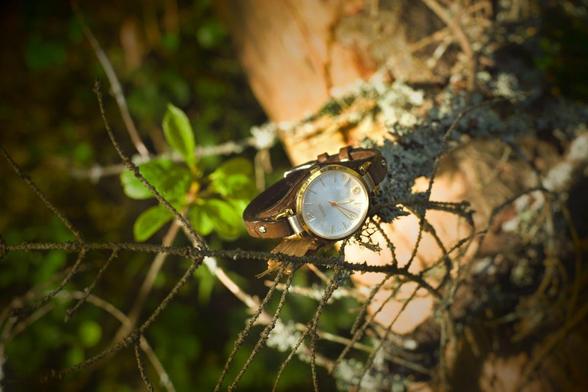 Photo shows a dark brown narrow watch strap. Strap has a layered look and consists of three parts. Strap is presented attached to the watch it belongs to.  