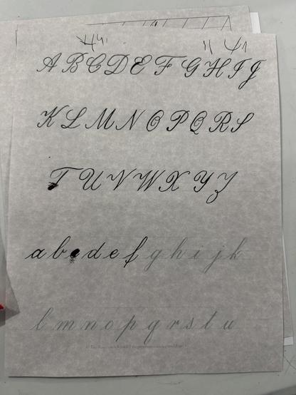 A sheet displaying uppercase and lowercase letters in a calligraphy script style, showcasing the alphabet from A to Z.