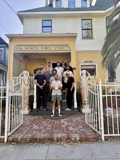 Photo of a bunch of people standing on the stairs of a house. I’m standing in the middle, holding my Apple Design Award, with the Apple logo facing the camera
