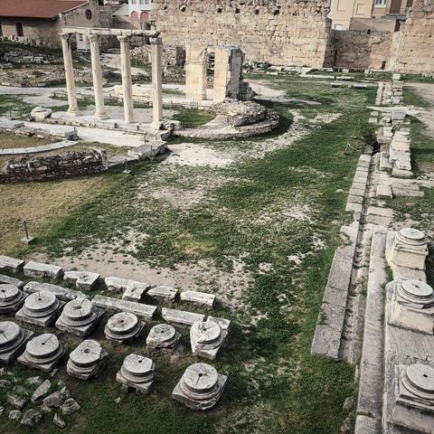 Ruinen eines alten Tempels o.ä. in Athen. Im Vordergrund sind Fundamentreste von Säulengängen zu sehen, in der Mitte stehen noch einzelne Säulen und im Hintergrund steht eine Mauer.