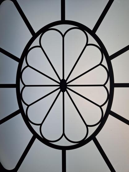 Eine große jugendstilartige Rosette aus Metall rahmt milchiges Glas ein.