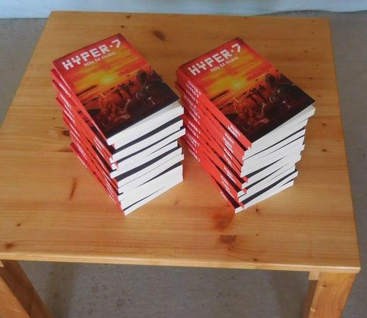 Two stacks of copies of the science fiction novel Hyper 7 on a small wooden table.