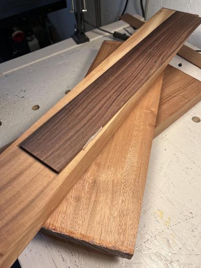 Einige recht dicke, gehobelte Stücke Holz, Mahagoni und Palisander, liegen auf einer weißen Werkbank.