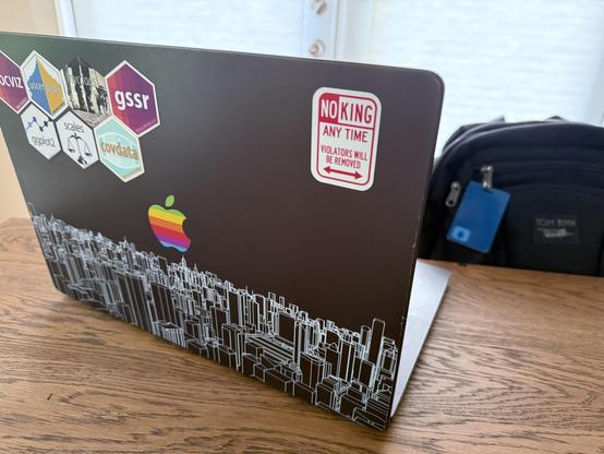 Laptop with NO KING ANY TIME sticker in the style of NY NO PARKING signs