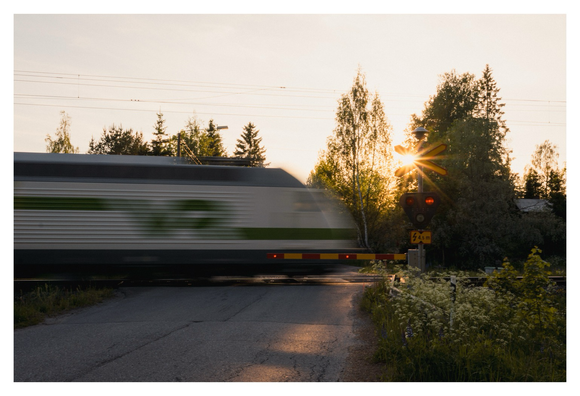 Finnischer Zug an Bahnübergang mit Bewegungsunschärfe