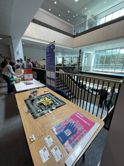 Laser cut and 3D printed parts of a braille machine laid out on a table by the stairs