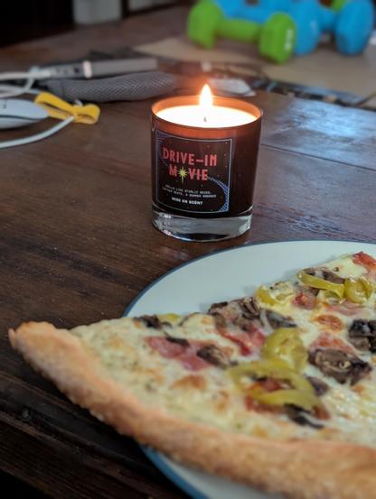 A Drive-in Movie candle next to some Pizza 