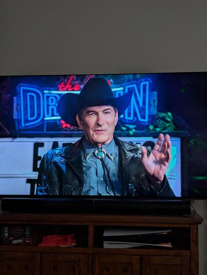 A TV with The Last Drive-in on it. This time, it's a tighter shot of Joe Bob as he educates the audience about the very first Drive-in theater.