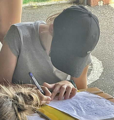Fillette à casquette penchée sur sa feuille à écrire 