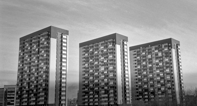 The monochrome photo shows three multi-storey identical buildings.
