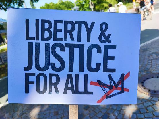 Sign: LIBERTY & JUSTICE FOR ALL and a crown Xed-out