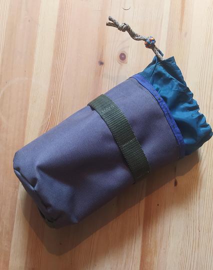 A small grey and green drawcord bag with multiple webbing mount points. 