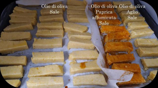 Plateau de four avec des bâtonnets de polenta sur du papier cuisson.
Trois rangées de bâtonnets avec de l'huile d'olive et du sel, une rangée avec de l'huile d'olive, du paprika fumé et du sel et une rangée avec de l'huile d'olive, de l'ail et du sel.