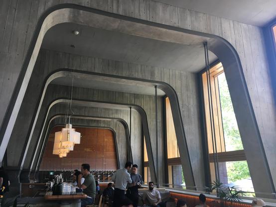 A vibrant restaurant scene showcasing a long bar and guests seated at tables, engaged in conversation.