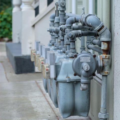 A closeup on a line of utility meters in front of a building
