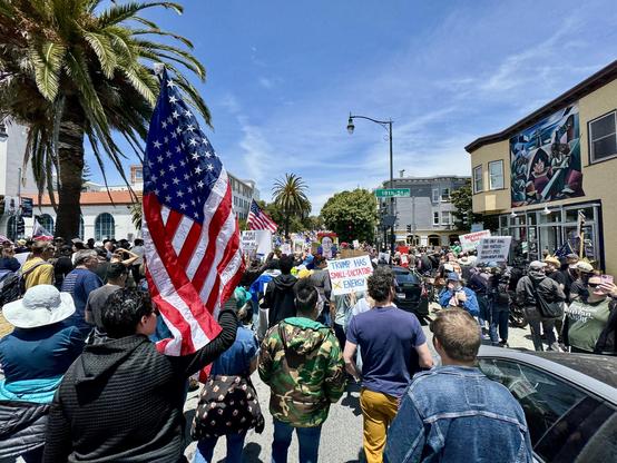 Another photo from the protest with several large American flags and protest signs. 