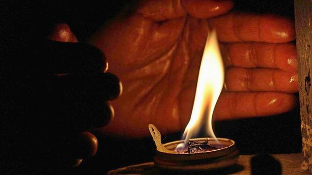 Hands around an oil lamp.