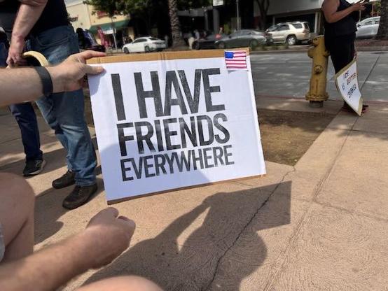 Protest sign with the phrase I HAVE FRIENDS EVERYWHERE and a tiny US flag crudely drawn in the corner