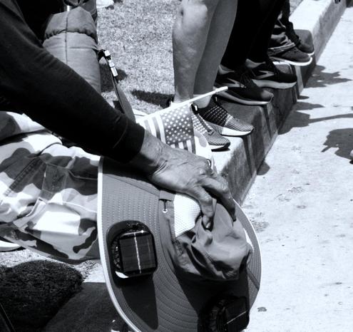 A man holds a small flag in his hand while he rests and tries to cool off at a rally in Santa Monica 