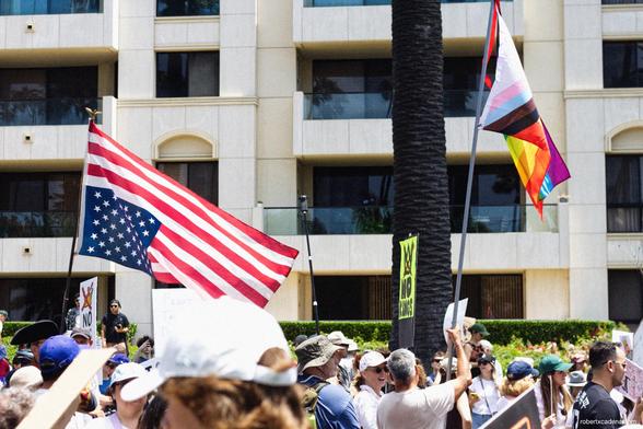 An upside down American flag and an LGBTQ flag at a rally