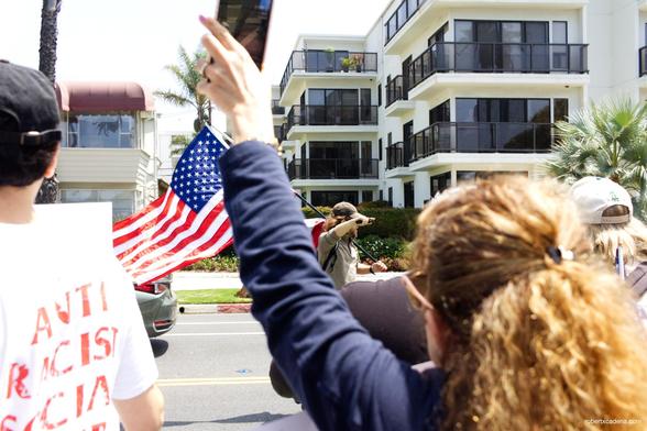 In the background the man with the flags riding by on his skateboard 