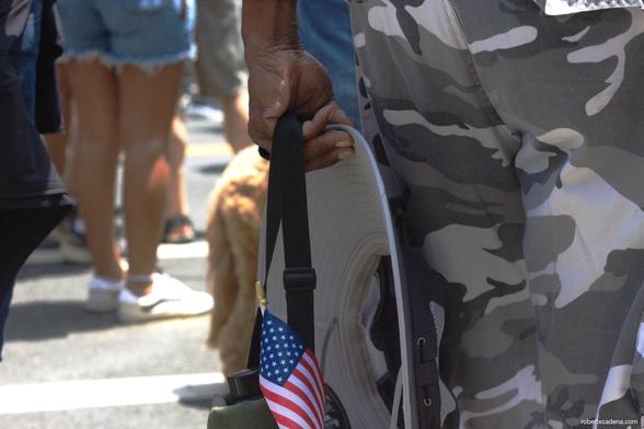 Closeup of a persons hand holding a hat and a small American flag