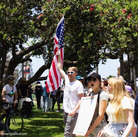 A man in sunglasses holds an American flag 