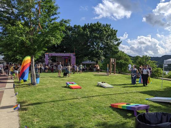 Photo of part of Pride of the music stage set up at Pride with rainbow color cornhole games.