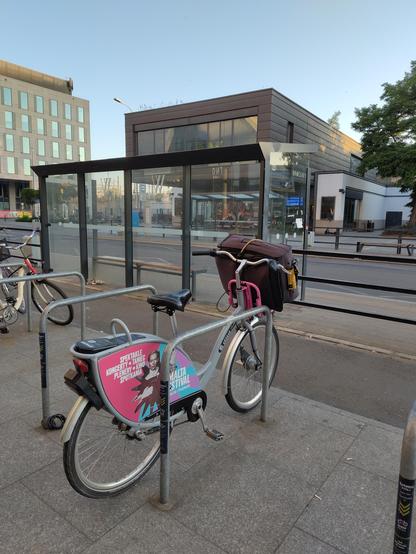 A shared bike (nextbike) with a travel suitcase in the front basket