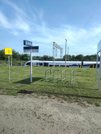 Platform on a train station. Some bike parking is visible. In the back a train is visible.
