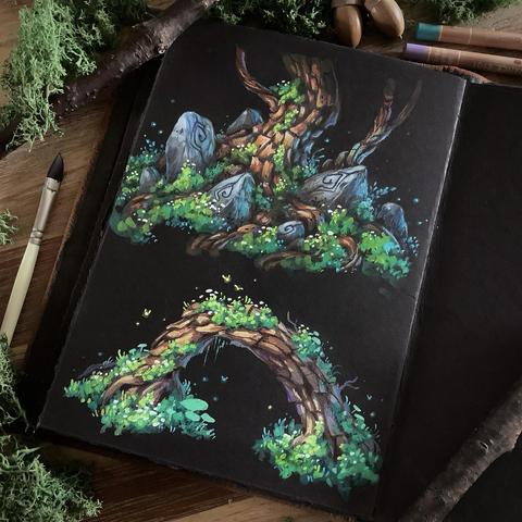 A photo of an open black paper sketchbook placed on a wooden table, surrounded by a paintbrush, coloured pencils, branches, and Icelandic moss for decoration. The page features two paintings. The one on top shows the base of a pine tree covered in moss and surrounded by rune stones intertwined with its roots. The bottom painting shows an arching tree trunk covered in moss, little glowing insects hovering around it.