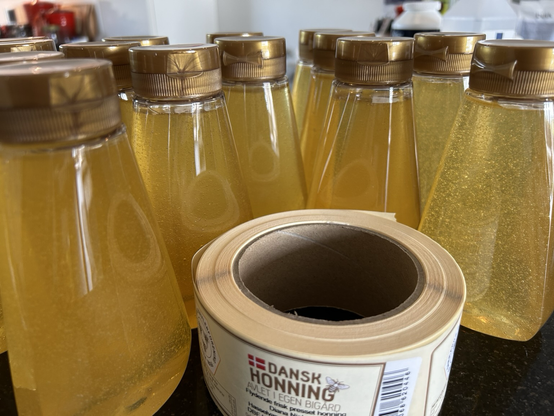 Freshly pressed honey in bottles and a roll of labels.