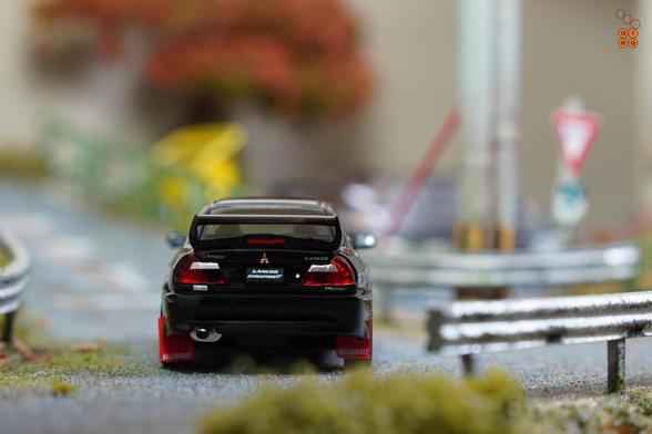 A rear sight view of Mitsubishi Lancer GSR Evolution V 1998 with Mud Flap, Pyrenees Black by Hobby Japan in 1:64 scale on AREA 164