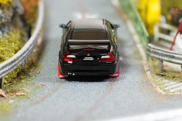 A rear sight view of Mitsubishi Lancer GSR Evolution V 1998 with Mud Flap, Pyrenees Black by Hobby Japan in 1:64 scale on AREA 164