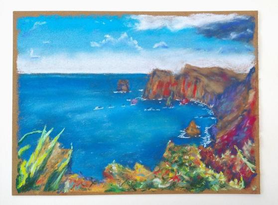 Painting of the sea clashing against cliffs. There are colorful spots in the cliffside. It's a painting on brown paper lying on a white table.
