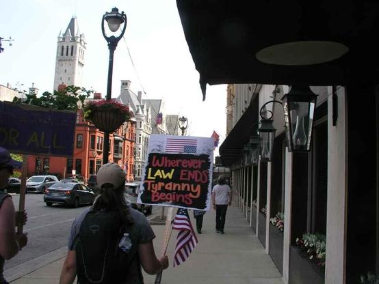 Protester leaving the Milwaukee WI NoKings day rally carrying sign that says: "Wherever Law Ends Tyranny Begins"