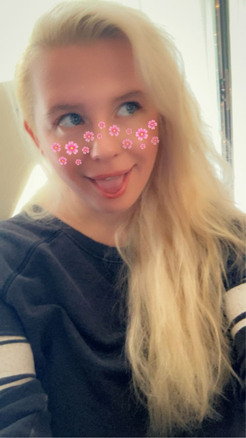 Selfie of Queen in a grey sweater with pink flowers from a snapchat filter on her face