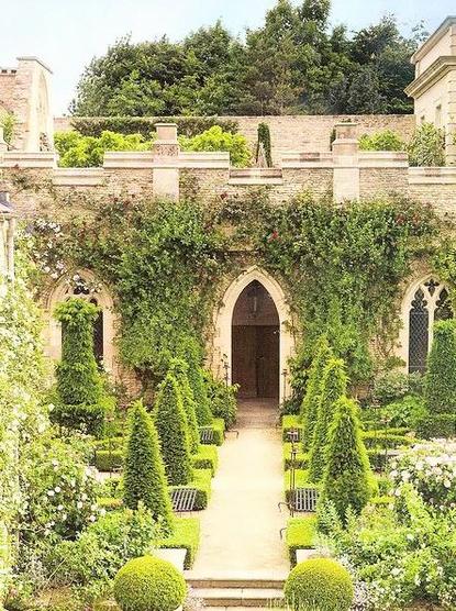 A church entry walkway decorated with beautiful bushes and flowers and with Ivy growing and covering most of the church walls 