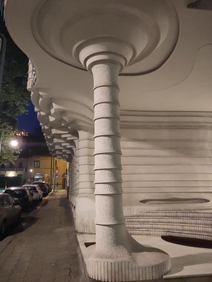 entrance of a residential building made of white stone/concrete (?) cut/molded in curvy shapes