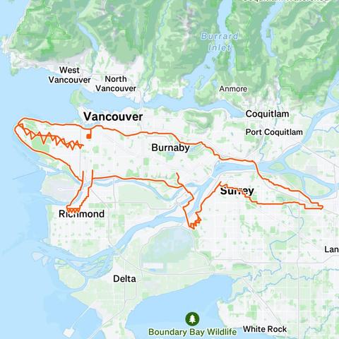 The image is a map of the Vancouver area, highlighting a route that resembles the shape of a crocodile. The route is outlined in orange and starts in Richmond, moving northward through Vancouver, then eastward through Burnaby, and finally southward through Surrey. The map includes several cities and geographical features, such as Burrard Inlet, the Fraser River, and Boundary Bay Wildlife. The crocodile-shaped route is prominently displayed, with its head in Richmond, its body through Vancouver,…