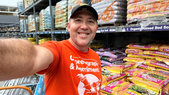 A person in an orange tshirt in what looks like garden section of homedepot store