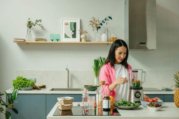 A woman is chopping vegetables and preparing ingredients in a modern kitchen