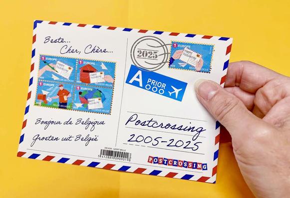 A hand holds Belgium’s new Postcrossing-themed stamp sheet, designed to look like a postcard and featuring colorful illustrations of postcard writing, mailing, and delivery.