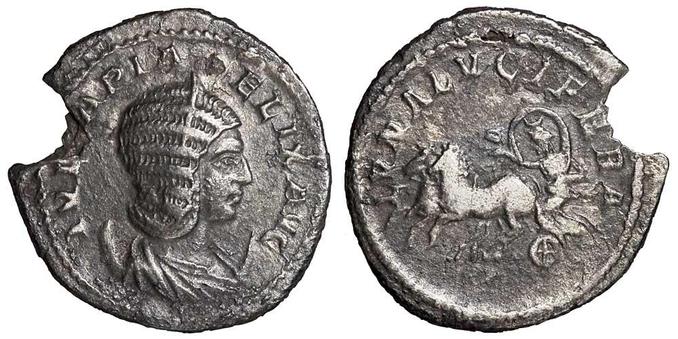 Silver coin depicting the moon goddess Luna, draped, crescent on her head, her cloak billowing in a circle around head, standing in a biga of horses prancing left, leaning forward, holding the reins with both hands. The words LUNA LUCIFERA, Luna the lightbearer, are minted around the scene.