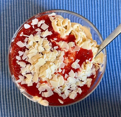 Spaghettieis mit Löffel darin in einem Glasschälchen. Das ganze steht auf einem blauen Tischset