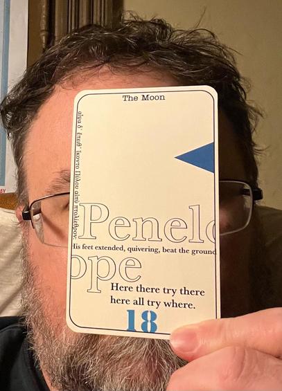 Tarot card representing the 18th & final Episode, Penelope (The Moon). The card is quite plane, bearing only a dark blue triangle on the right border and a pair of quotes from Ulysses. The card mostly obscures the face of a bearded man. 
