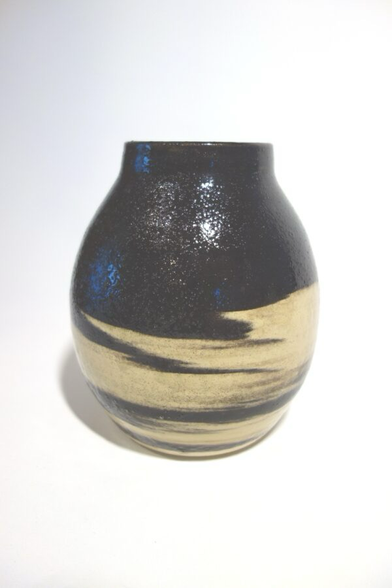Vase oben und unten schwarz, in der Mitte weiß mit schwarzen Streifen, so wie sich die beiden Tonsorten eben auf der Drehscheibe miteinander verbunden haben.