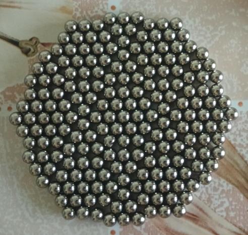 A hexagon of small ball bearing-sized magnets. The magnets are grouped into smaller triangles and larger hexagons that together make up the overall hexagon.