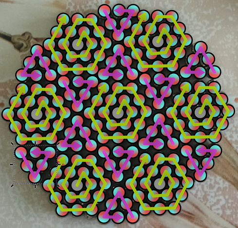 Image of the ball bearing-like magnets again, this time overlaid with yellow clockwise spirals over each of the hexagons and purple counterclockwise spirals over each of the triangles. The magnets themselves have been covered by circles filled with a gradient from red on one end to cyan on the other.